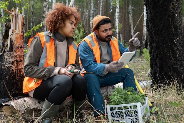 A volunteer assisting a wildlife biologist in monitoring nesting birds, with the biologist holding binoculars and the volunteer recording data on a clipboard, both wearing appropriate field gear.
