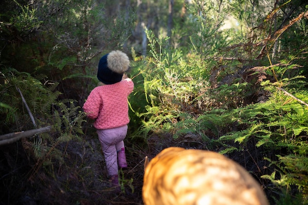 A group of children participating in a guided nature walk through a National Wildlife Refuge, led by a volunteer who is pointing out different plants and animals along the trail.